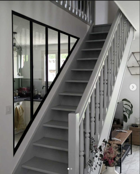 Verrière triangulaire sur-mesure sous un escalier, profilés noirs, vue depuis le rez-de-chaussée.